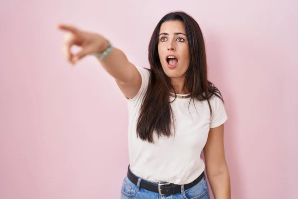 Young Brunette Woman Standing Pink Background Pointing Finger Surprised Ahead — Stock Photo, Image