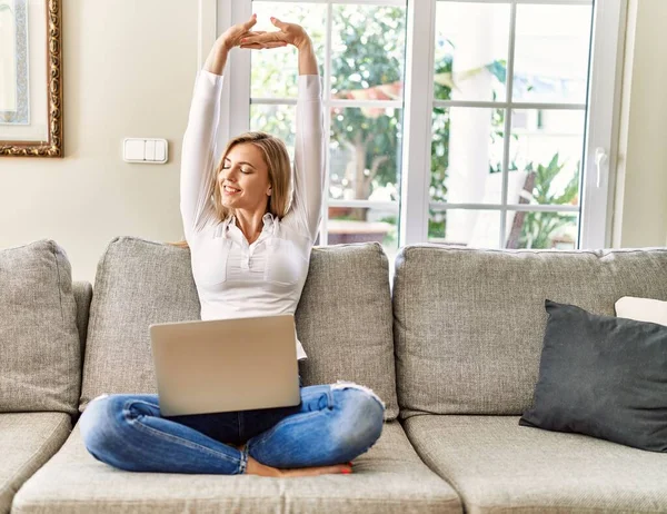 Jonge Blonde Vrouw Stretching Armen Met Behulp Van Laptop Thuis — Stockfoto