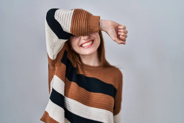 年轻美丽的女人穿着条纹毛衣 罩在孤立的背景上 眼睛上 胳膊上挂着笑脸 笑容可亲 盲目概念 — 图库照片