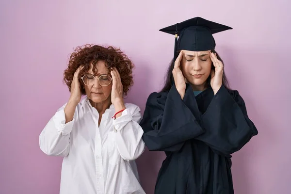 ストレスのために頭の中で痛みのために頭の上に手で卒業キャップと儀式のローブを身に着けているヒスパニック系の母親と娘 片頭痛 — ストック写真