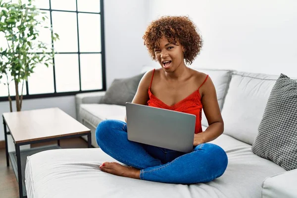Young African American Woman Sitting Sofa Home Using Laptop Winking — Φωτογραφία Αρχείου