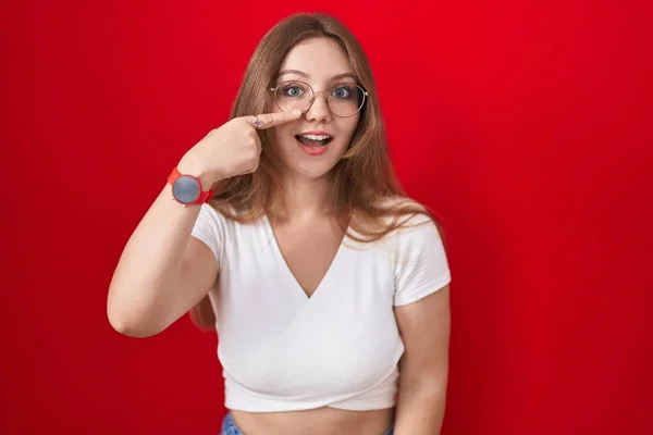 Mladá Běloška Stála Nad Červeným Pozadím Ukazovala Prstem Tvář Nos — Stock fotografie