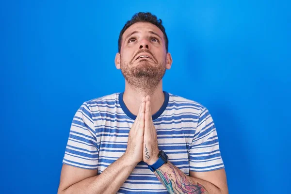 Joven Hombre Hispano Pie Sobre Fondo Azul Mendigando Orando Con —  Fotos de Stock