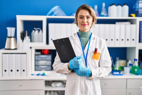 Young woman scientist hoplding clipboard at laboratory