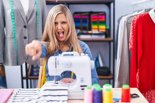Blonde Woman Dressmaker Designer Using Sew Machine Pointing Displeased Frustrated — 图库照片