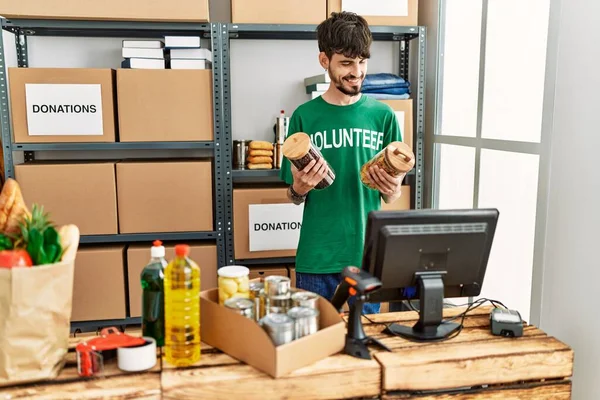 Jonge Spaanse Man Draagt Vrijwilligersuniform Houdt Voedsel Vast Een Liefdadigheidscentrum — Stockfoto