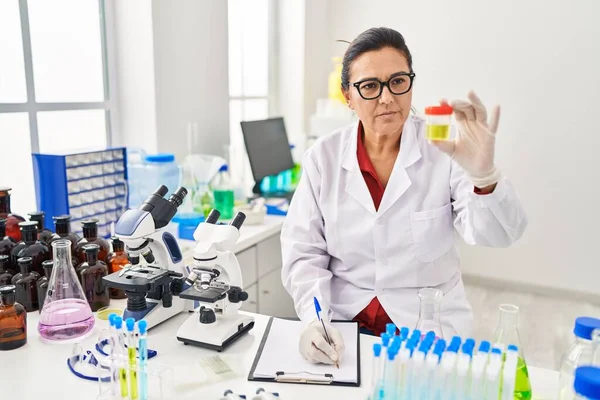 Middle Age Hispanic Woman Wearing Scientist Uniform Analysing Urine Test — стоковое фото