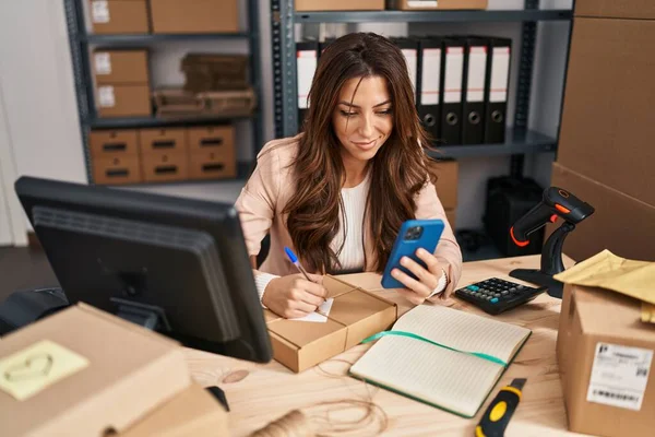 Young Hispanic Woman Ecommerce Business Worker Using Smartphone Writing Package — Stok fotoğraf