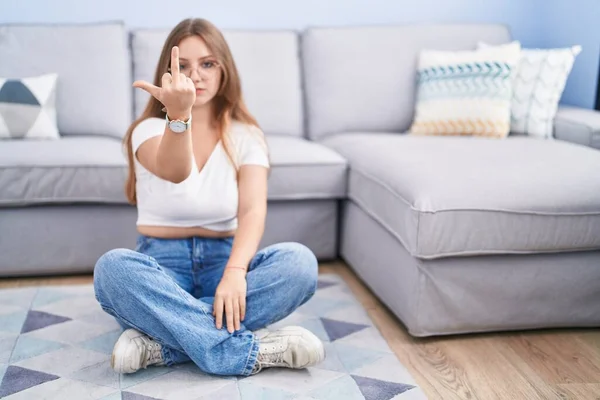 Young Caucasian Woman Sitting Floor Living Room Showing Middle Finger — Stok fotoğraf