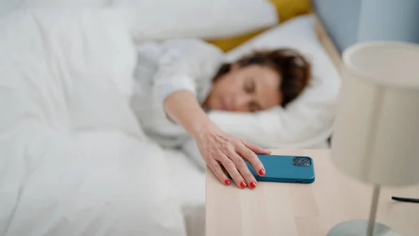 Hiszpanka Średnim Wieku Wyłącza Alarm Smartfonie Leżący Łóżku Sypialni — Zdjęcie stockowe