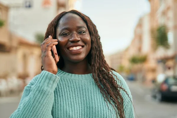 年轻的非洲女人在城市的电话里开心地微笑着 — 图库照片