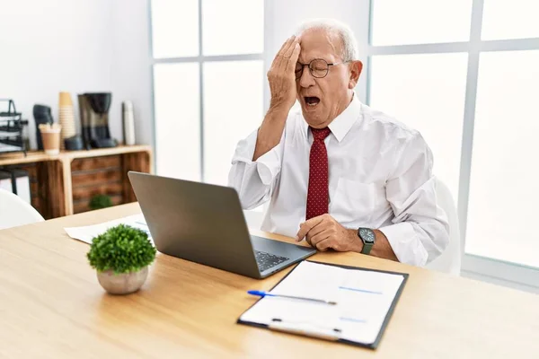 オフィスで働いているシニアの男性は 疲れて半分の顔 口を手で覆い コンピュータのラップトップを使ってあくびをしています 痛みで顔が痛い — ストック写真