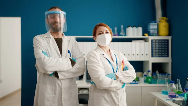 男と女身に着けています科学者制服立ってとともに腕交差ジェスチャーで実験室 — ストック写真