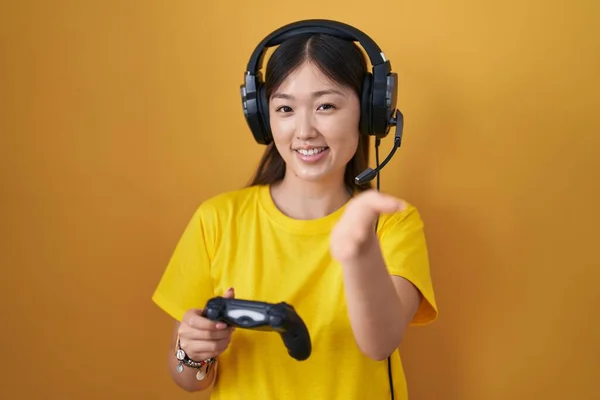 中国的年轻女子正在玩电子游戏 手握控制器 友好地微笑 握手致意和欢迎 成功的商业 — 图库照片