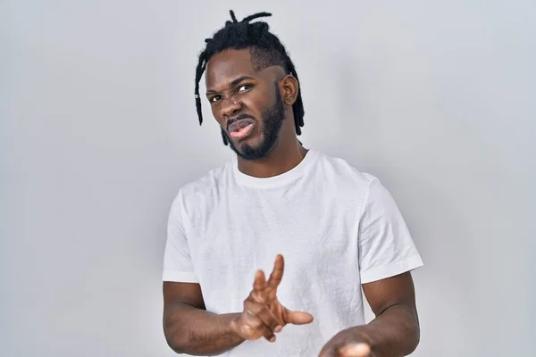 African man with dreadlocks wearing casual t shirt over white background disgusted expression, displeased and fearful doing disgust face because aversion reaction. with hands raised
