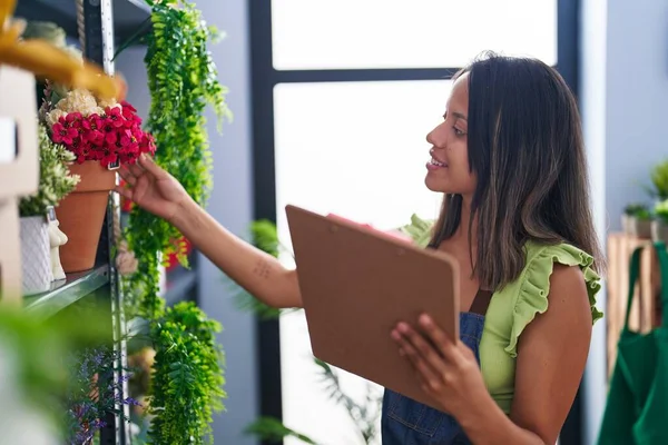 Young Hispanic Woman Florist Reading Document Organize Shelving Florist Store — Zdjęcie stockowe
