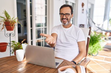 Orta yaşlı bir adam evde bilgisayar kullanıyor. Gülümsüyor, avuç içi kadar yardım ve kabul görüyor.. 