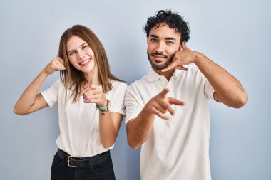 Gündelik giysiler giymiş genç bir çift gülümsüyor telefonda konuşuyor ve seni işaret ediyor. Ara beni.. 