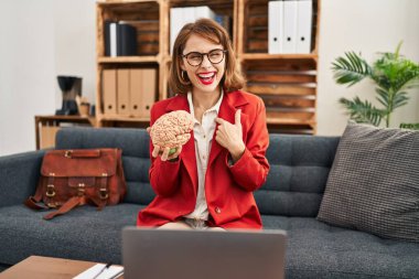 Muayenehanedeki genç esmer kadın beyni elinde tutarak gülümseyen mutlu ve gururlu birini işaret ediyor. 