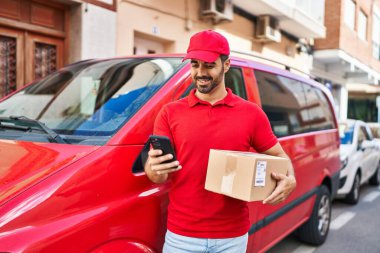 Genç İspanyol kurye sokakta akıllı telefon paketi kullanıyor.