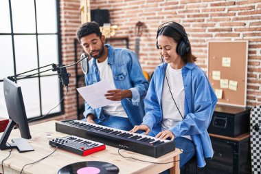 Man and woman musicians singing song playing piano at music studio