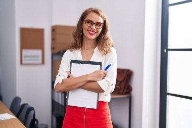Genç, güzel, İspanyol bir iş kadını. Ofiste elinde bir panoyla gülümsüyor.