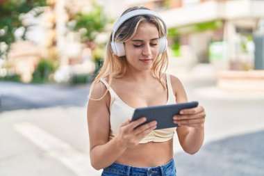 Genç sarışın kadın gülümsüyor. Caddedeki dokunmatik evde video izlerken kendinden emin.