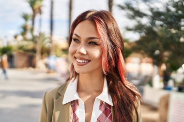 Beyaz bir kadın gülümsüyor parkın kenarına bakıyor.