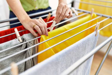 Orta yaşlı İspanyol kadın çamaşırhanede pıhtı asıyor.