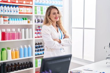 Young beautiful hispanic woman pharmacist smiling confident standing with arms crossed gesture at pharmacy