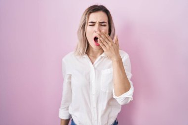 Pembe arka planda duran genç ve güzel bir kadın esnemekten sıkılmış, ağzıyla ağzını kapatmaktan sıkılmış. Huzursuz ve uykulu.. 