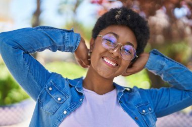 Afro-Amerikalı kadın parkta kendinden emin bir şekilde gülümsüyor.