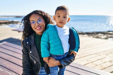 Mother and son hugging each other sitting on bench at seaside