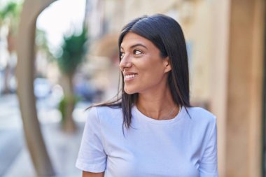 Young beautiful hispanic woman smiling confident looking to the side at street