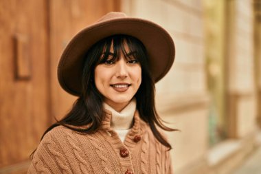 Açık havada gülümseyen, kışlık şapkalı esmer kadın.