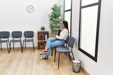 Bekleme odasında kendine güvenen, gülümseyen genç Afrikalı Amerikalı kadın.