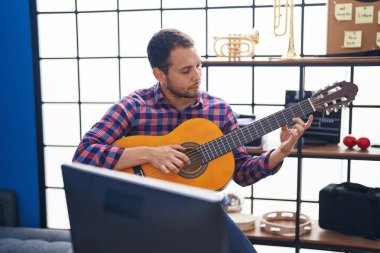 Young man musician playing classical guitar at music studio