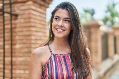 Young beautiful hispanic woman smiling confident looking to the side at street