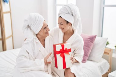 Mother and daughter wearing bathrobe surprise with gift at bedroom