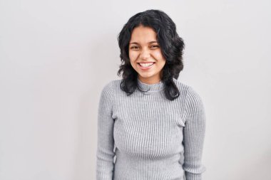 Esmer, esmer bir kadın. Arka planda dikilip kameraya bakıyor. Seksi bir ifadeyle, neşeli ve mutlu bir yüzle.. 