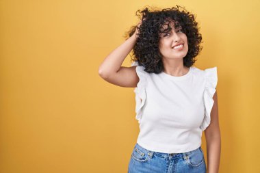 Sarı arka planda duran genç ortadoğulu kadın soru sorup kafasını karıştırıyor. Şüpheyle kararsız, kafa kafaya düşünerek. Düşünceli kavram. 