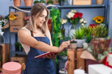 Young caucasian woman florist reading notebook at florist