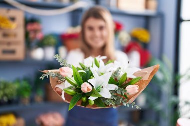 Young woman florist holding bouquet of flowers at florist