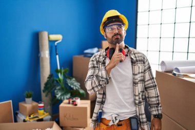 Sakallı genç İspanyol bir adam evini yenilemek için çalışıyor. Düşünceleri şüphe üzerine yoğunlaşmış, çenesi parmaklarıyla yukarı bakıyor ve merak ediyor. 