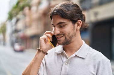 Genç İspanyol adam gülümsüyor. Kendine güveniyor. Sokakta akıllı telefondan konuşuyor.