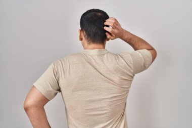 Young arab man wearing casual t shirt backwards thinking about doubt with hand on head 