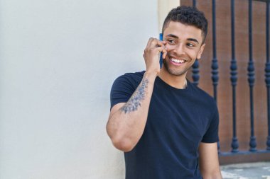 Afro-Amerikalı adam gülümsüyor. Kendine güveniyor. Akıllı telefondan konuşuyor.