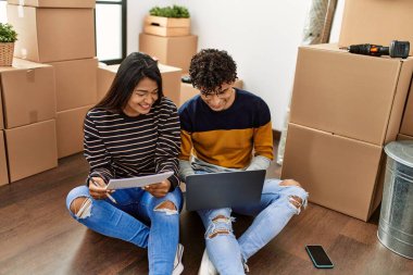Genç Latin çift yeni evlerinde dizüstü bilgisayar kullanıyor..