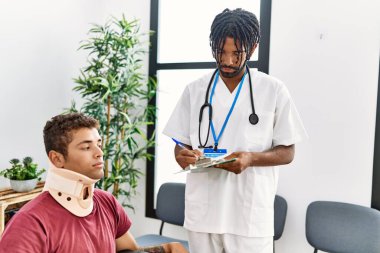 Tekerlekli sandalyede oturan iki erkek fizyoterapist ve hasta hastane bekleme odasında tıbbi danışmanlık yapıyorlar.