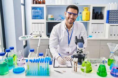 Latin asıllı genç bilim adamı laboratuardaki belgeye yazı yazıyor.